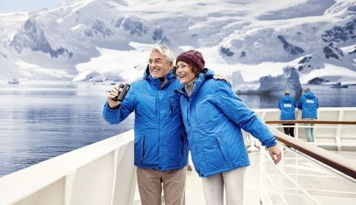 Antarktispärchen an Bord vor schneebedeckten Bergen