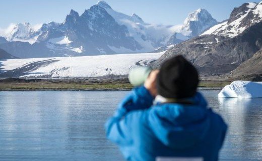 Fotograf vor schneebedeckten Bergen und Wasser