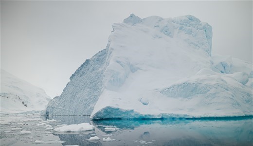 Riesiger Eisberg und Spiegelungen im klaren Wasser.