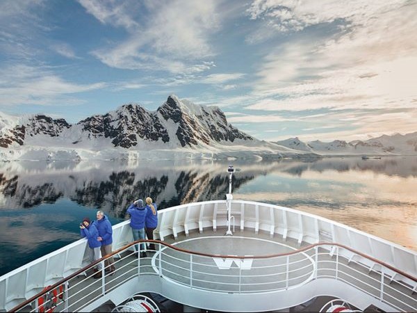 An Bord des Antarktis Schiffes stehen Gäste und schauen die umliegende Landschaft an