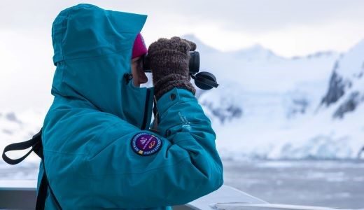 Frau beobachtet Wildlife durch Fernglas bei Antarktis Reise