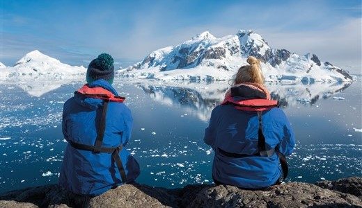 Zwei Antarktis Reisende genießen den Ausblick auf die Berg-und Eislandschaft.