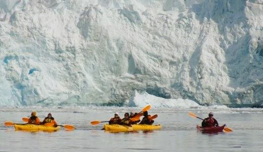 Drei Kajaks vor Eisberg in der Antarktis